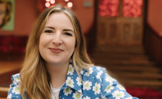 Abbie McCarthy poses in a blue jacket with daisy print
